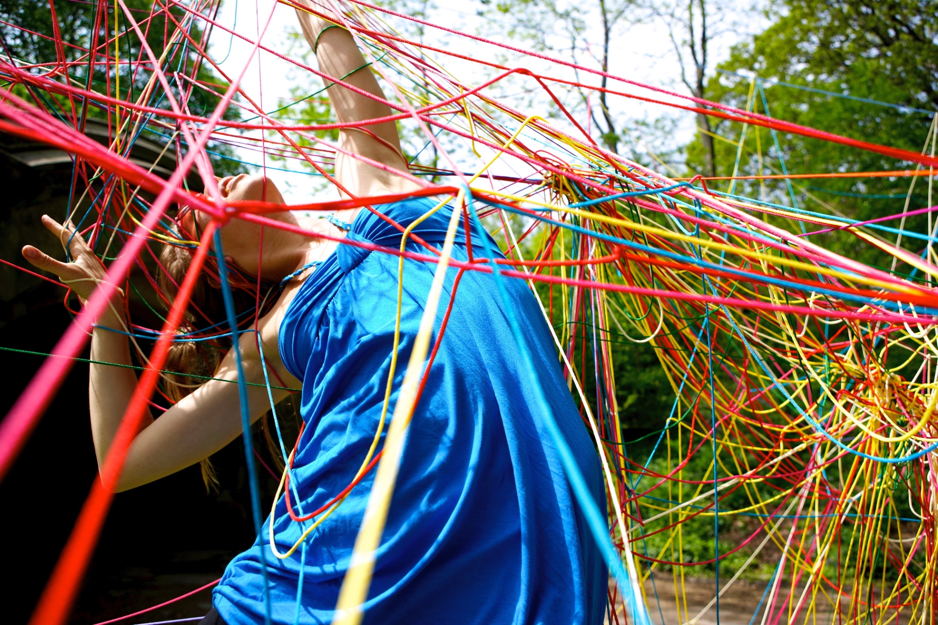 A dancer moving inside a bright red and yellow string web
