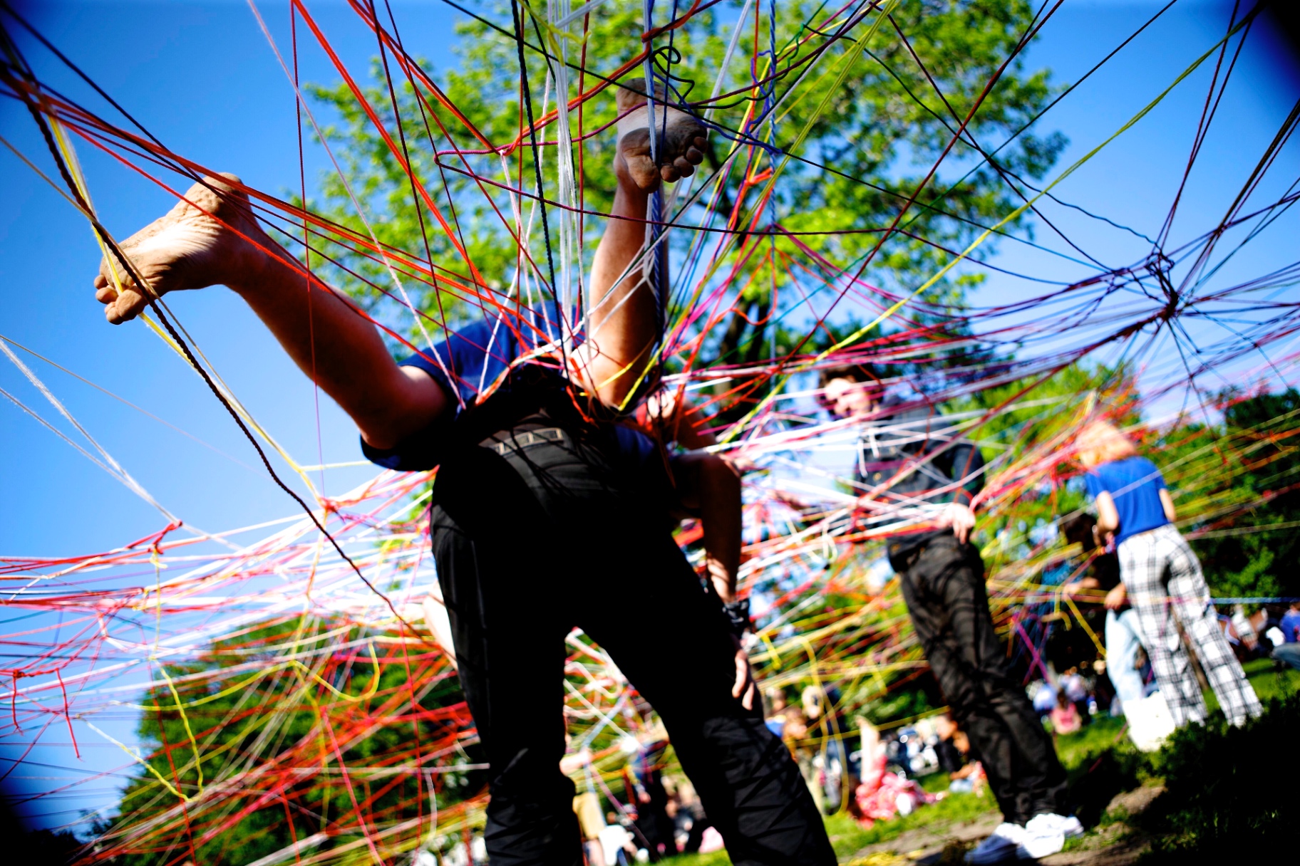 People tangled and playing inside a giant string web in a park
