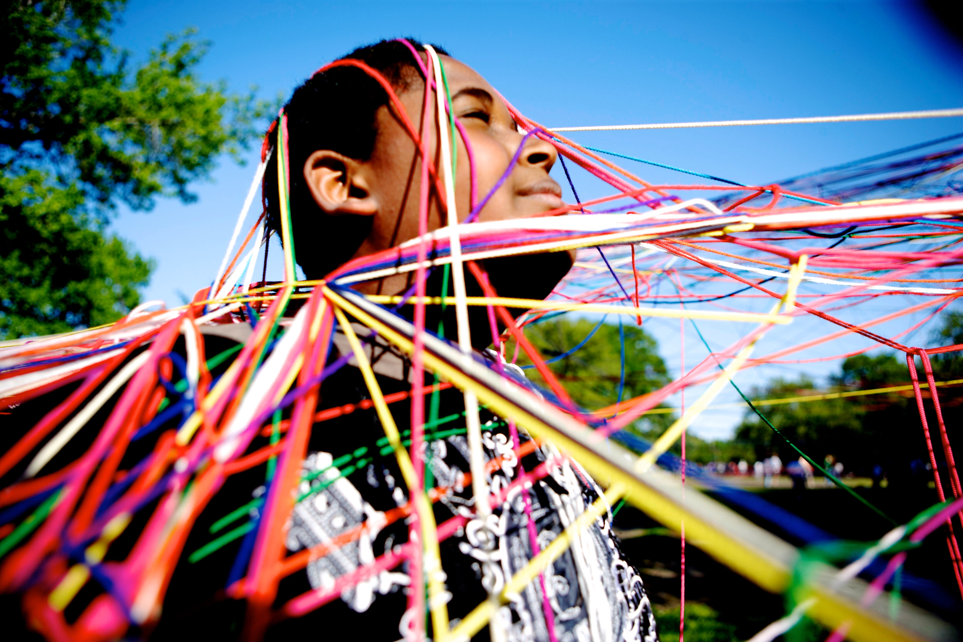 A person surrounded by colorful strings woven around them
